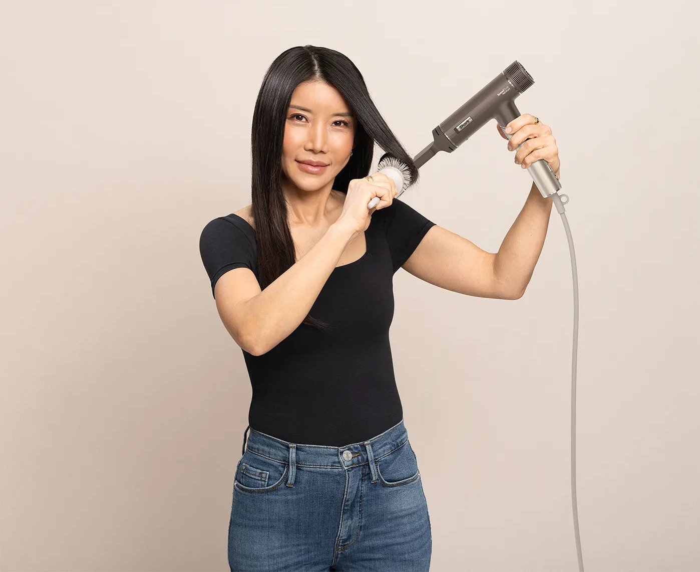 Жінка сушить і випрямляє волосся феном Shark Із круглою щіткою для створення гладкої зачіски