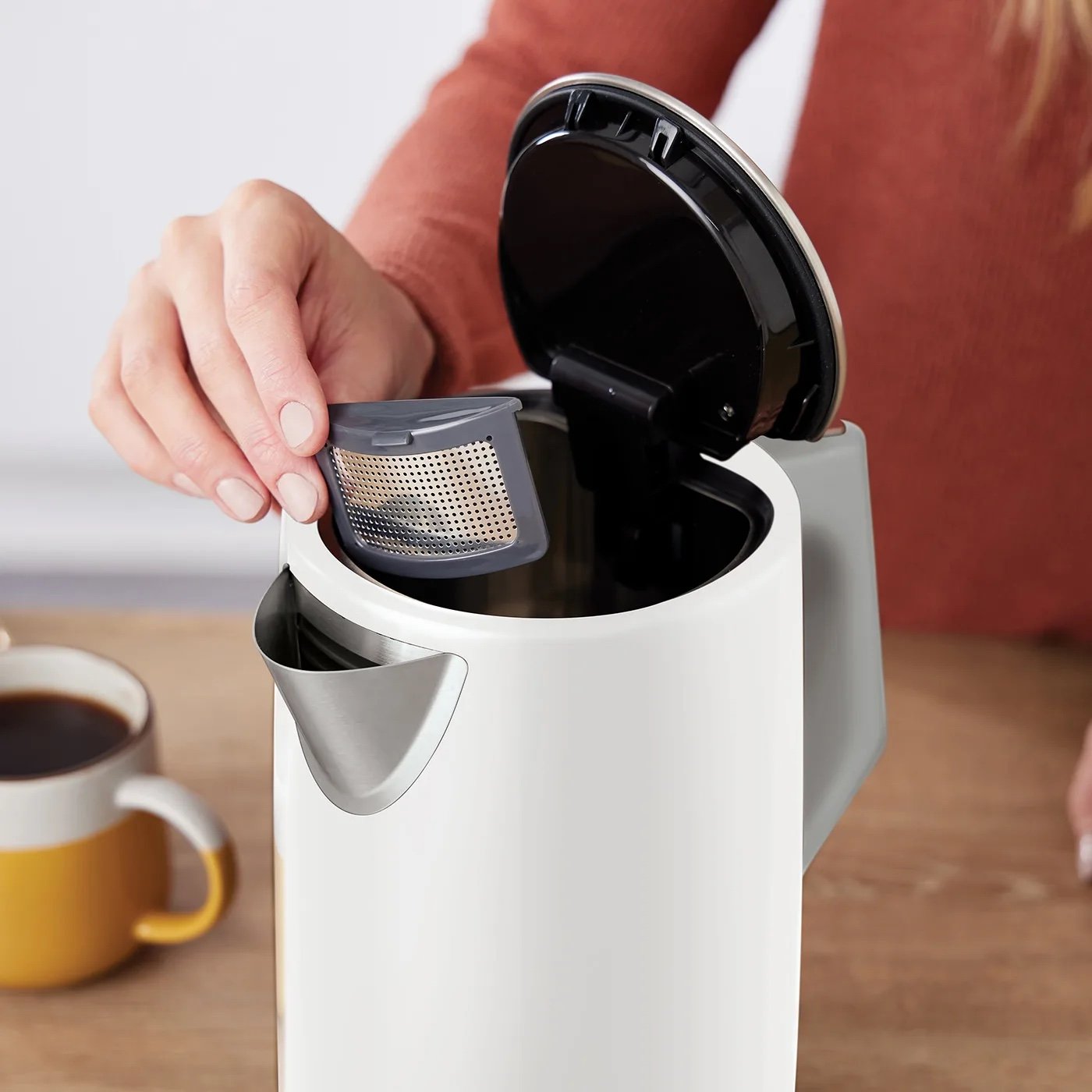 Людина знімає фільтр із носика електрочайника Ninja білого кольору з сірими елементами