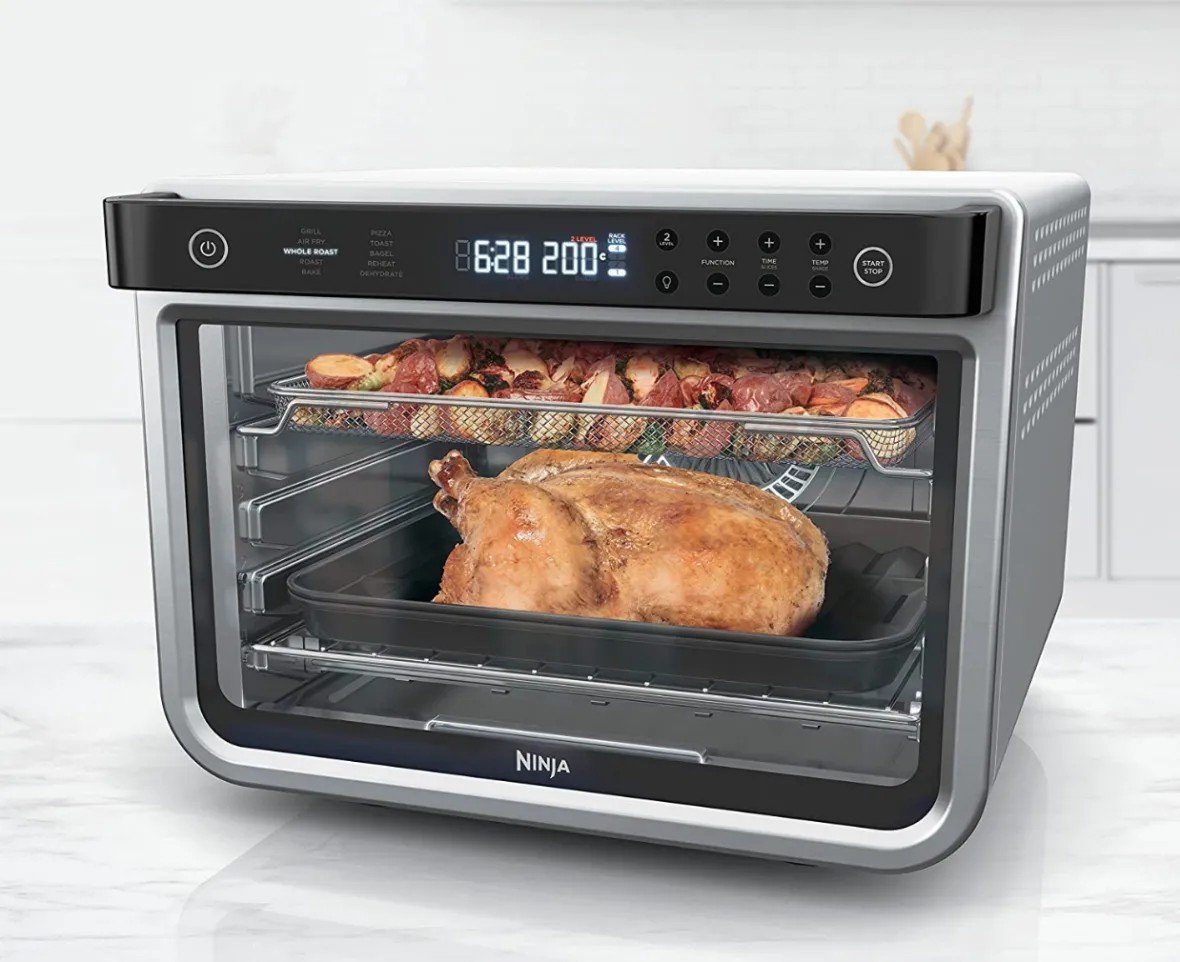 Духовка Ninja із прозорими дверцятами, всередині запікається курка та овочі на двох рівнях