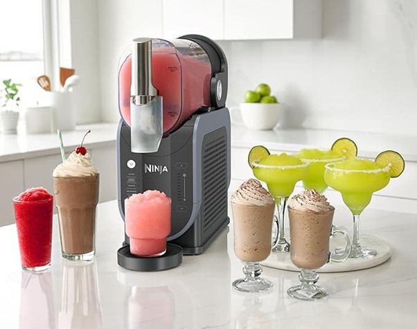 Льодогенератор Ninja на кухонному столі поруч із келихами з фрапе, смузі та коктейлями