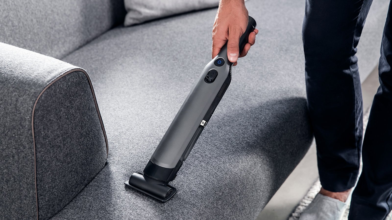 Ручний пилосос Shark очищує тканинний диван у вітальні.