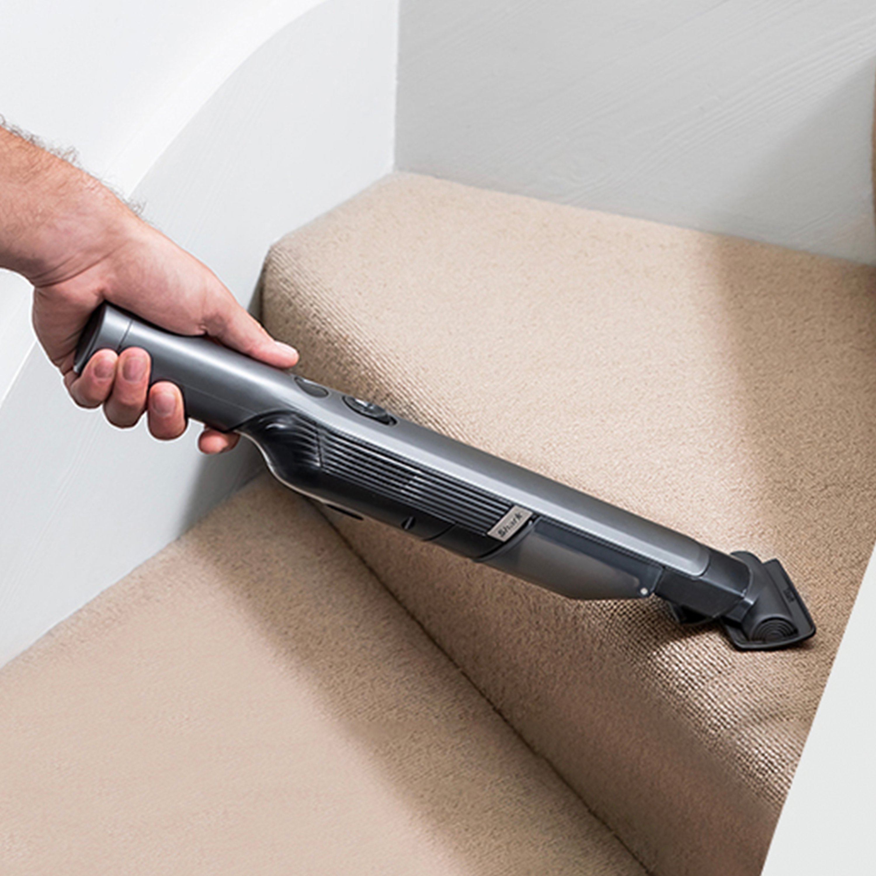 Очищення килимових сходів ручним пилососом Shark із вузькою насадкою.