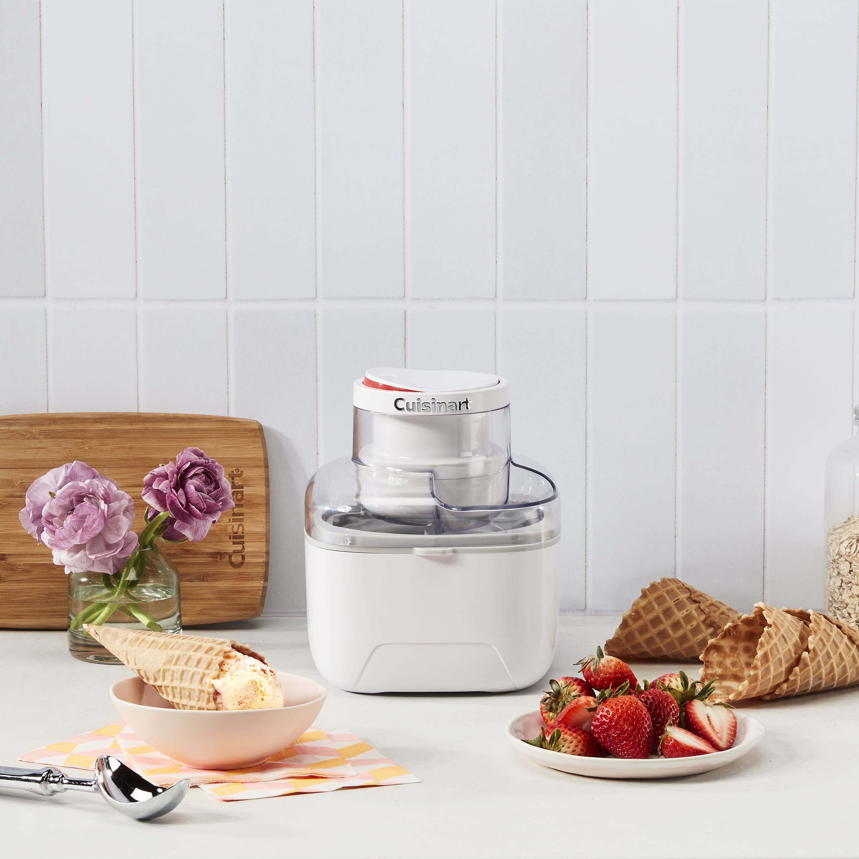 Морозивниця Cuisinart на кухні поруч із полуницею, вафельними ріжками та десертом