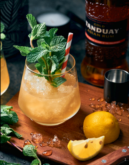 Келих коктейлю з ромом Tanduay Asian Rum Gold, льодом, м'ятою та лимоном на дерев'яній дошці.